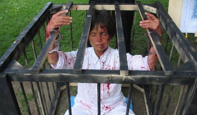 A Falun Gong practitioner protests by posing in a cage (Minghui)