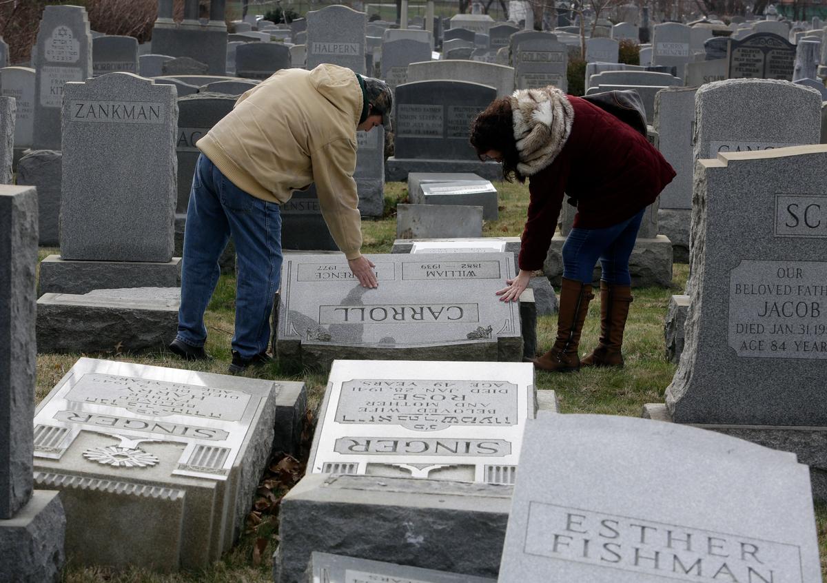 Joe Nicoletti and Ronni Newton of the Taconey Holmesburg town watch group pay their respects at a damaged headstone in Mount Carmel cemetery n Philadelphia on Feb. 27, 2017. (AP Photo/Jacqueline Larma)