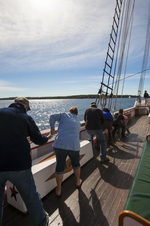 Passengers help hoist a sail on the Victory Chimes ship off the coast of Maine on Sept. 28, 2016. (Channaly Philipp/Epoch Times)