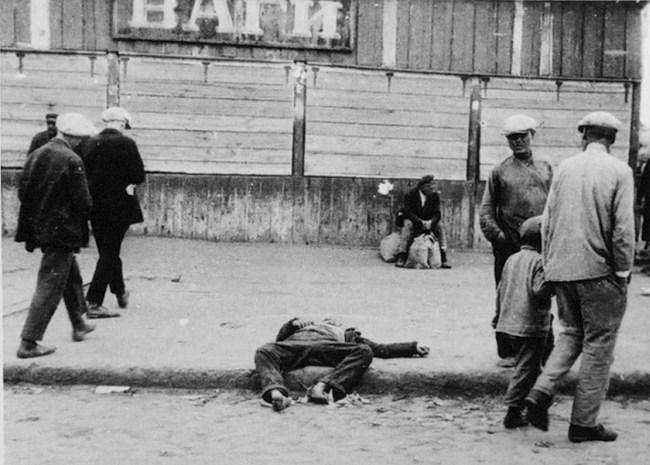 Passers-by and the corpse of a starved man on a street in Kharkiv, 1932 (Public Domain)