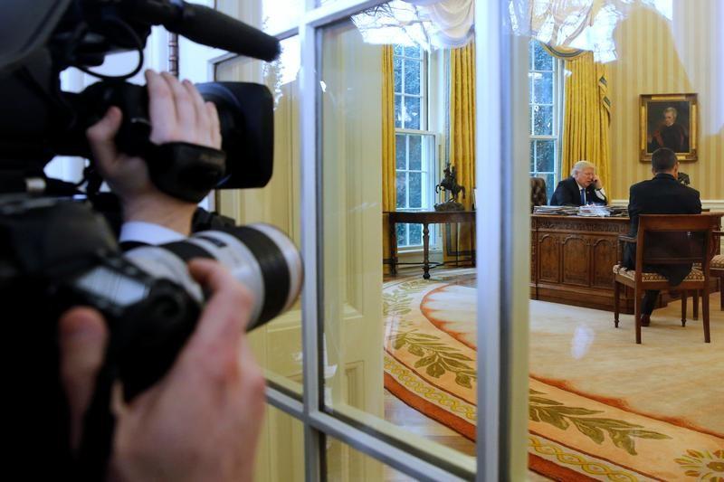 Photographers look on as U.S. President Donald Trump speaks by phone with Germany's Chancellor Angela Merkel in the Oval Office at the White House in Washington, U.S. Jan. 28, 2017. (REUTERS/Jonathan Ernst)