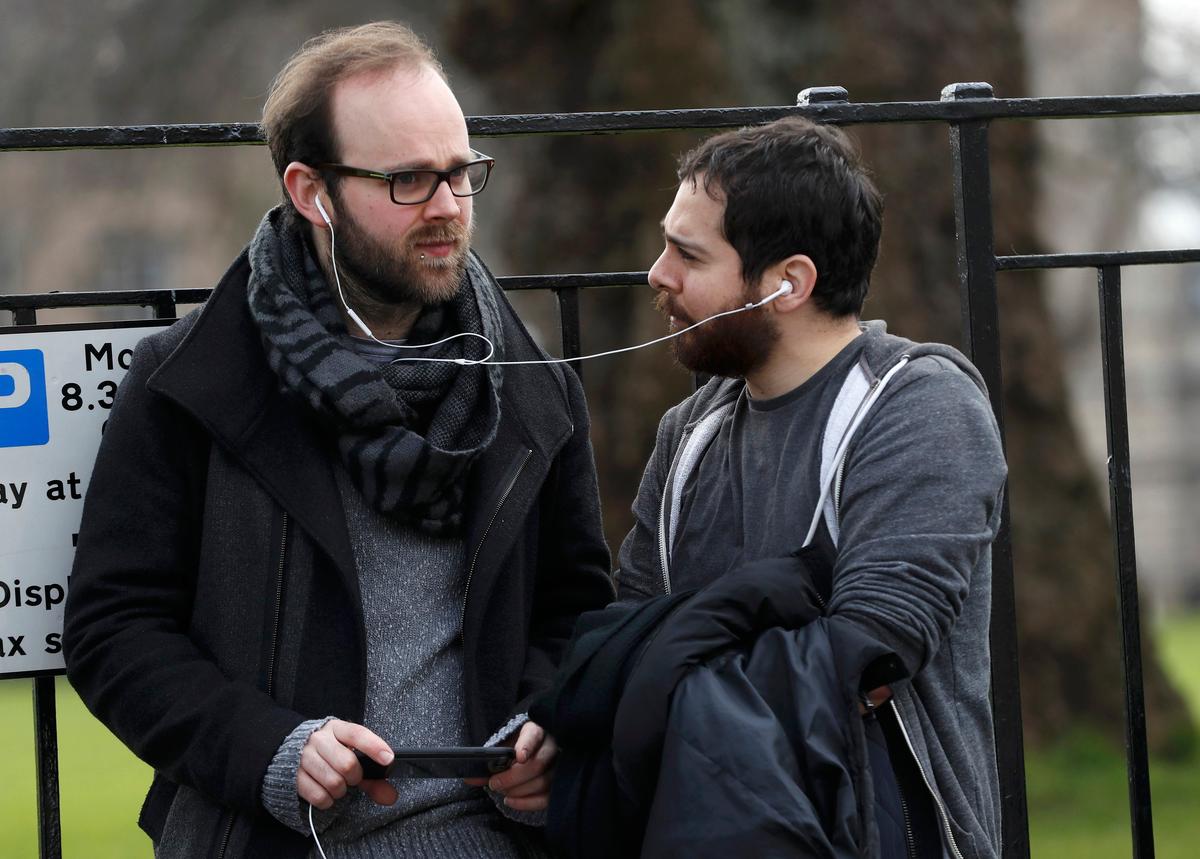 People listen and watch on their mobile devices as Scotland's First Minister Nicola Sturgeon demands a new independence referendum to be held in late 2018 or early 2019, once the terms of Britain's exit from the European Union have become clearer, outside Bute House, in Edinburgh, Scotland, Britain on March 13, 2017. (REUTERS/Russell Cheyne)