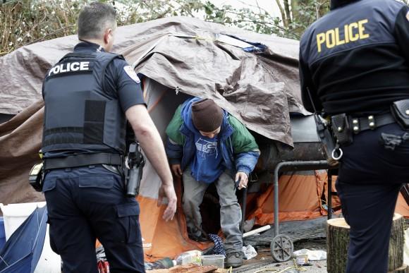 Leroy Henry (C) steps out of his tent in the woods to talk with police officer Kevin Davis (L) and Sgt. Mike Braley in Everett, Wash., on Feb. 16, 2017. As overdose deaths from opioids and heroin spiked the mayor of Everett took steps to tackle the epidemic devastating this working-class city north of Seattle. (AP Photo/Elaine Thompson)