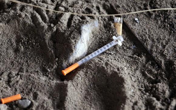 A discarded syringe sits in the dirt with other debris under a highway overpass where drug users are known to congregate in Everett, Wash., on Feb. 16, 2017. (AP Photo/Elaine Thompson)