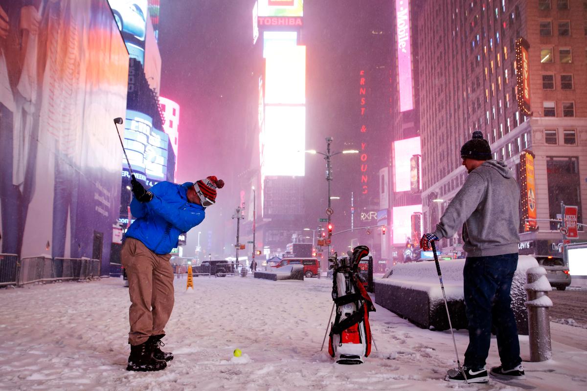 Two men play golf with a tennis ball as a snowstorm sweeps through Times Square on in New York on March 14, 2017. (AP Photo/Mark Lennihan)