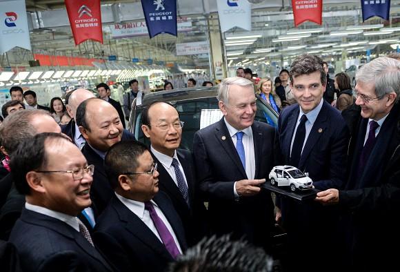 French Prime Minister Jean-Marc Ayrault (3rd R) prepares to present a model car to Chinese managers on a visit to the Dongfeng Peugeot-Citroën Automobile plant on Dec. 7, 2013, in Wuhan, China. The following year, Chinese state-owned Dongfeng became an equal shareholder in PSA Peugeot Citroën, the leading carmaker in France. (PETER PARKS/AFP/Getty Images)