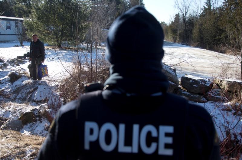 A man is confronted by a Royal Canadian Mounted Police officer as he prepares to cross the U.S.-Canada border leading into Hemmingford, Quebec. (REUTERS/Christinne Muschi)