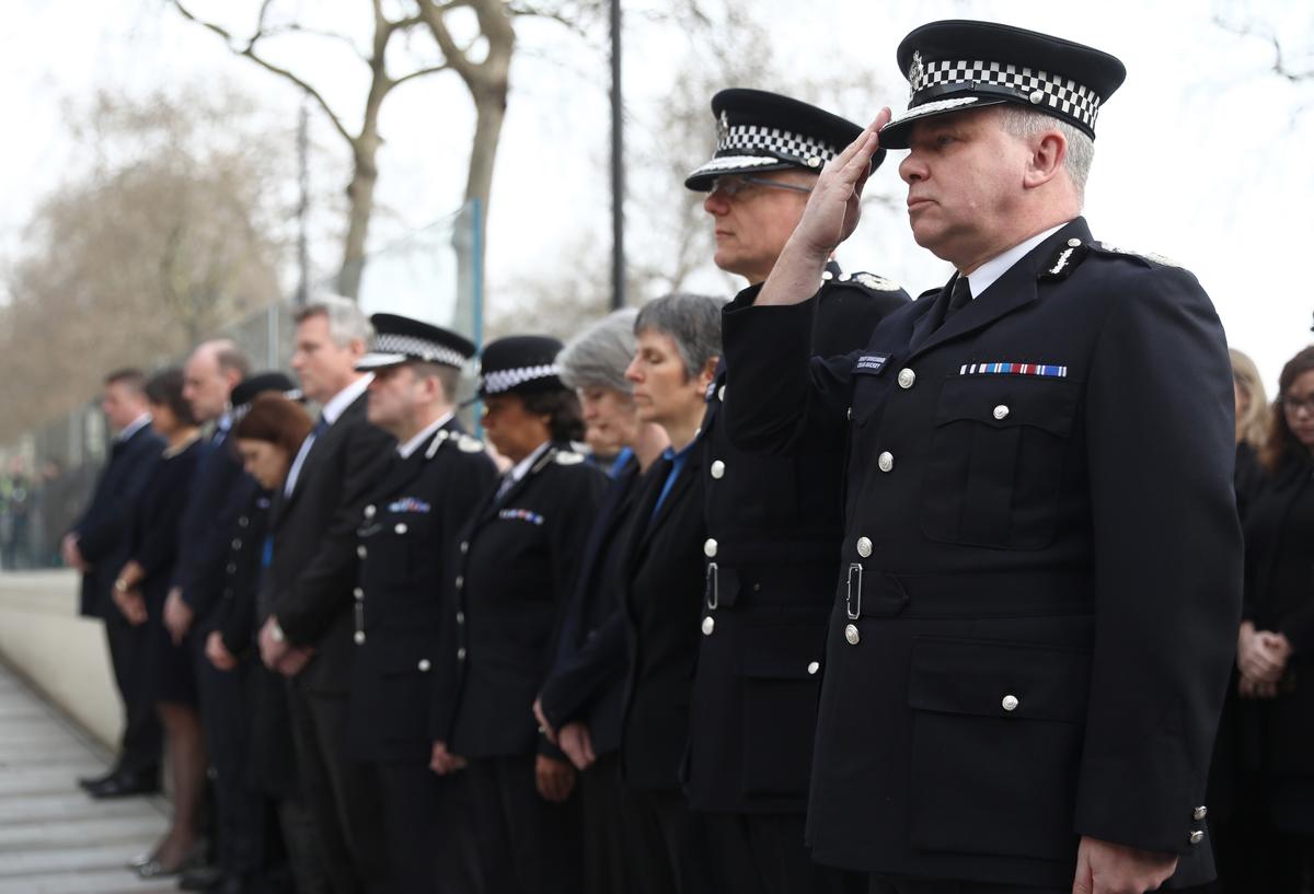 Police officers salute during a minute's silence outside New Scotland Yard. (REUTERS/Neil Hall)
