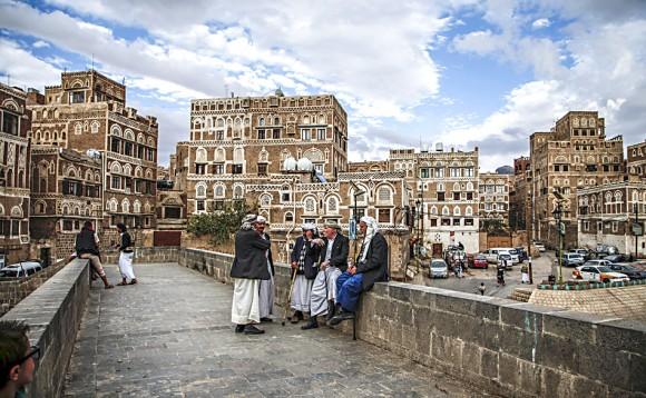 Yemenis sit and talk by the ledge of a bridge with the UNESCO-listed buildings of the old city of the Yemeni capital Sanaa in background behind them, on Feb. 15, 2017. (MOHAMMED HUWAIS/AFP/Getty Images)