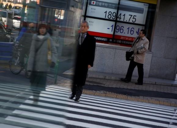 People walk past an electronic board showing stock prices outside a brokerage at a business district in Tokyo, Japan, Jan. 23, 2017. (REUTERS/Kim Kyung-Hoon)