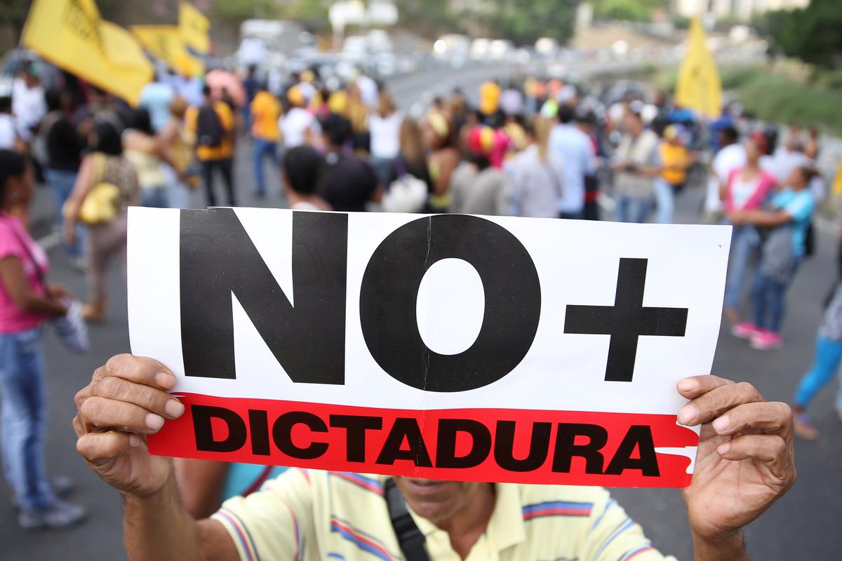 Opposition supporters holding a placard that reads, "No more dictatorship" shout slogans as they block a highway during a protest against Venezuelan President Nicolas Maduro's government in Caracas, Venezuela on March 31, 2017. (REUTERS/Carlos Garcia Rawlins)