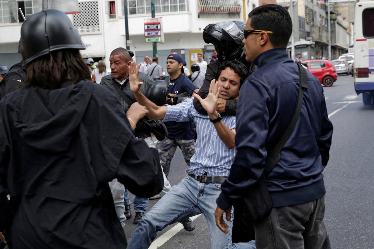 A pro-government supporter wearing a helmet grabs an opposition supporter during a protest against Venezuelan President Nicolas Maduro's government outside the Venezuelan Prosecutor's office in Caracas, Venezuela on March 31, 2017. (REUTERS/Marco Bello)