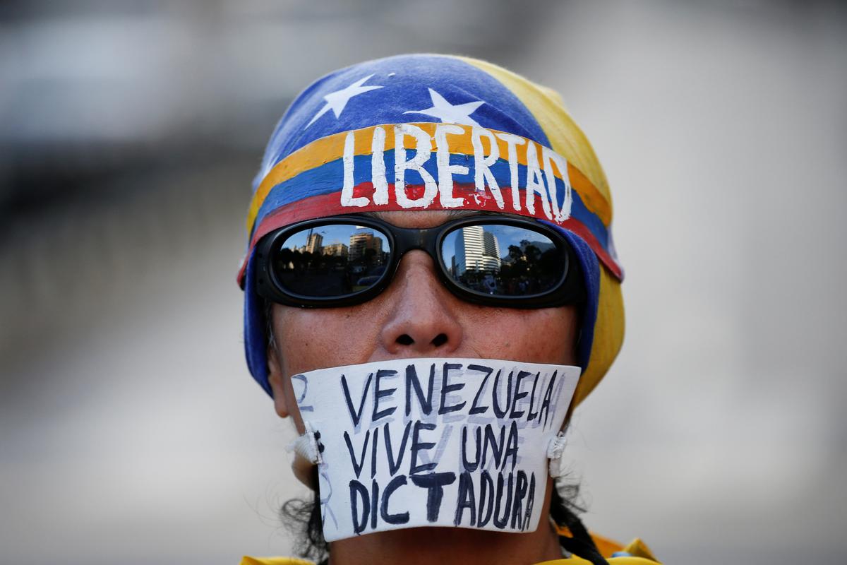 An opposition supporter with a sign that reads, "Venezuela lives a dictatorship", take part in a protest against Venezuelan President Nicolas Maduro's government in Caracas, Venezuela March 31, 2017. (REUTERS/Carlos Garcia Rawlins)