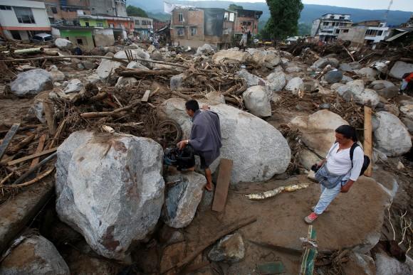 People walk on a street destroyed after flooding and mudslides, caused by heavy rains leading several rivers to overflow, pushing sediment and rocks into buildings and roads, in Mocoa, Colombia April 2, 2017. (REUTERS/Jaime Saldarriaga)