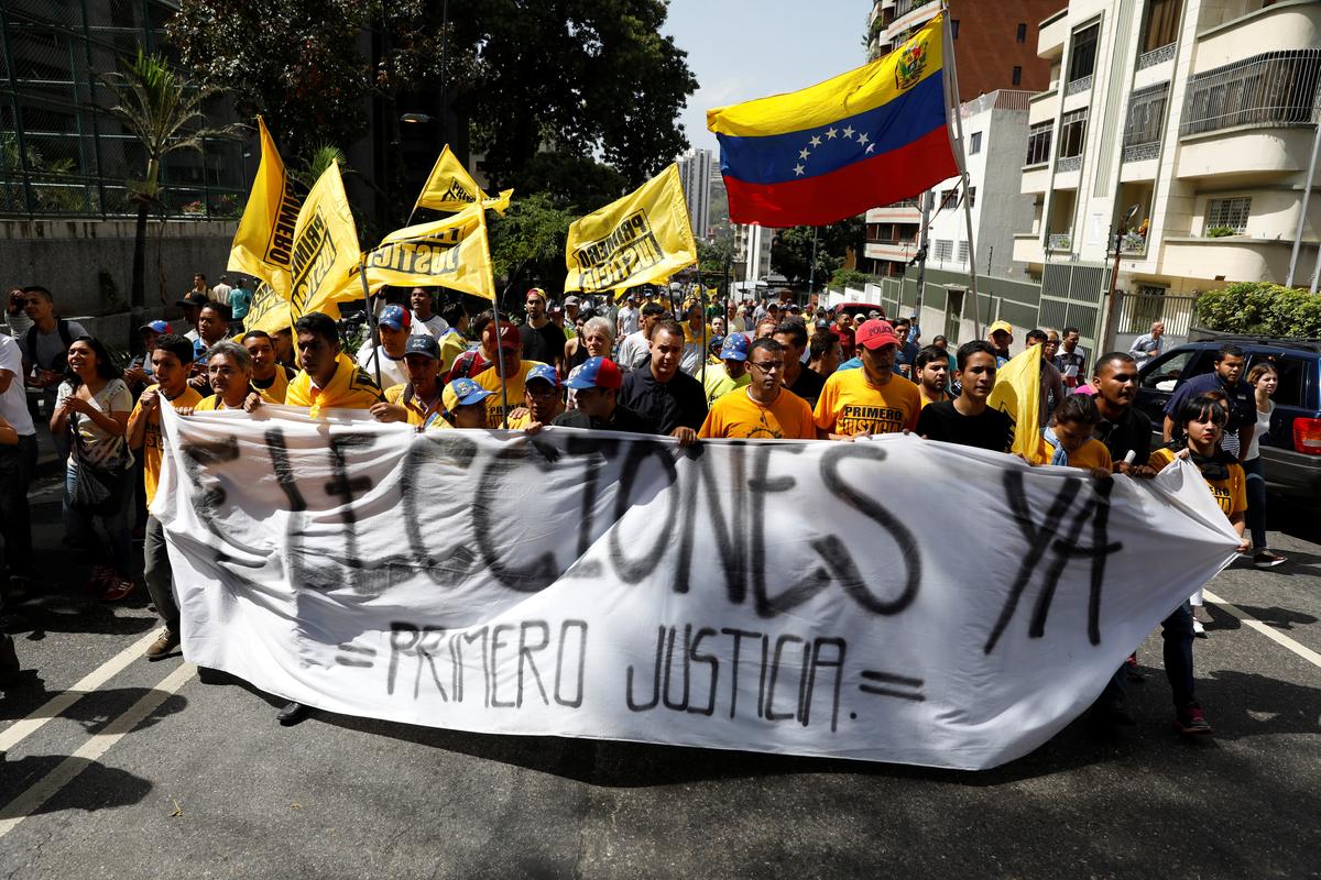 Demonstrators carry a banner reading "Elections now, justice first" during an opposition rally in Caracas, Venezuela on April 4, 2017. (REUTERS/Carlos Garcia Rawlins)
