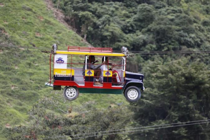 Tourists ride a cable car in the form a of a Chiva, a bus used to serve rural routes, in Pitalito, Colombia, on April 5, 2017. The ride called "La Chiva Voladora" costs about $0.70 and runs about 800 meters (875 yards) from one side of a hill to another. (AP Photo/Fernando Vergara)