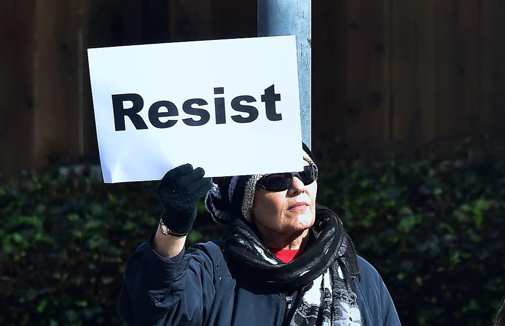A woman holds a placard reading "Resist" as demonstrators gathered along El Camino Real in San Mateo, California on Inauguration Day on Jan. 20, 2017. (FREDERIC J. BROWN/AFP/Getty Images)