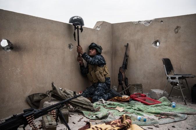 An Iraqi federal policeman uses a helmet on a stick to try and draw fire from an ISIS sniper in an attempt to make him reveal his position during the battle to recapture west Mosul in Iraq on April 13. (Carl Court/Getty Images)