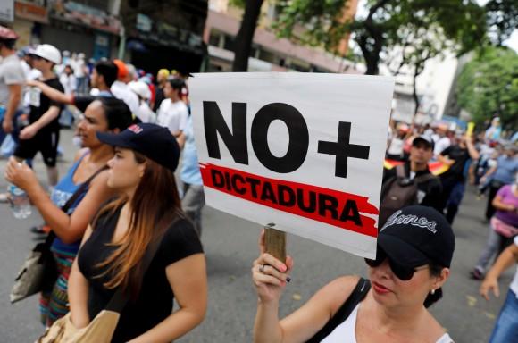 Demonstrators rally during the so-called "mother of all marches" with a sign that reads "No more dictatorship" against Venezuela's President Nicolas Maduro in Caracas, Venezuela April 19, 2017. (REUTERS/Carlos Garcia Rawlins)
