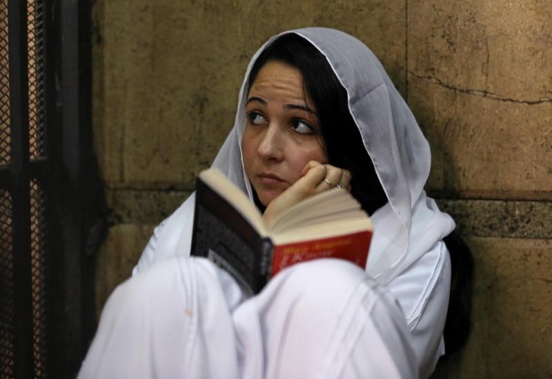 Aya Hijazi, founder of a non-governmental organisation that looks after street children, sits reading a book inside a holding cell as she faces trial on charges of human trafficking, sexual exploitation of minors, and using children in protests, at a courthouse in Cairo, Egypt on March 23, 2017. (REUTERS/Mohamed Abd El Ghany)