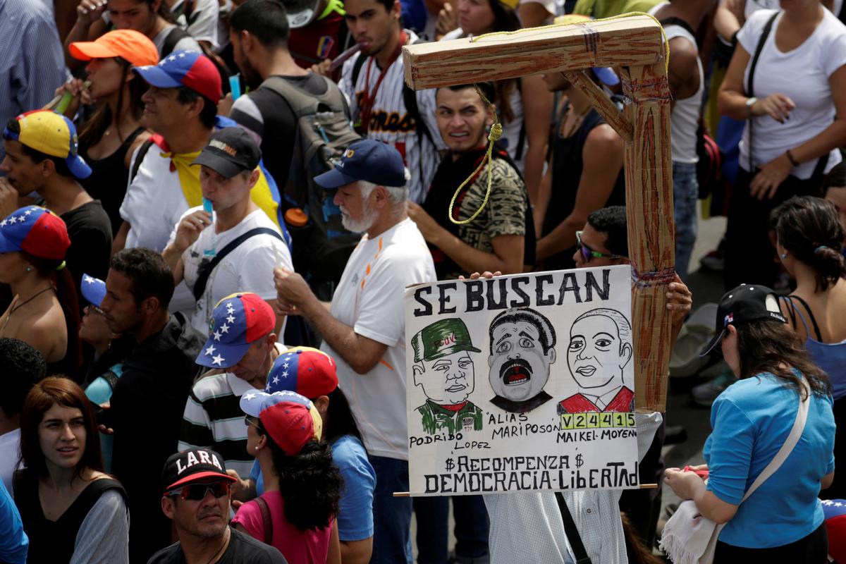 Protesters carry a placard depicting (L-R) Venezuela's Defense Minister Vladimir Padrino Lopez, Nicolas Maduro and Venezuela's Supreme Court President Maikel Moreno that reads "Wanted" during a rally in Caracas, Venezuela on April 24, 2017. (REUTERS/Marco Bello)