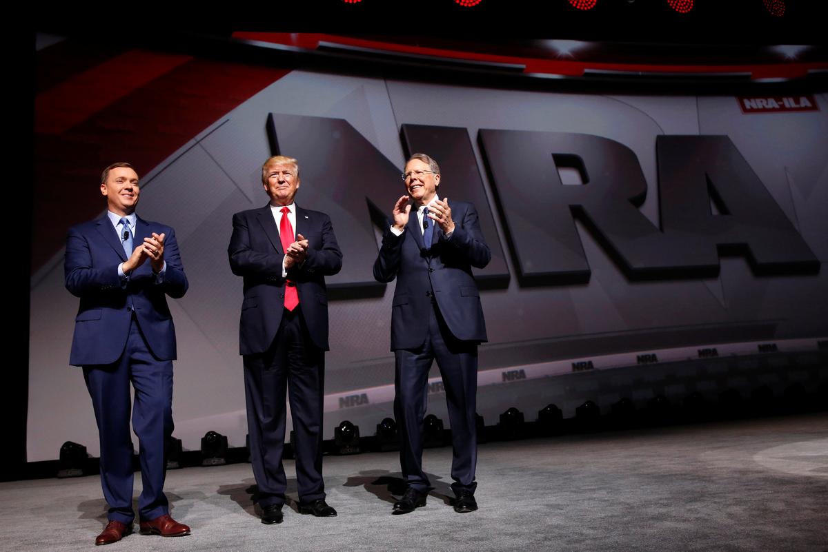 NRA Executive Director Chris Cox (L) and Executive Vice President and CEO Wayne LaPierre (R) welcome President Donald Trump (C) onstage to deliver remarks at the National Rifle Association (NRA) Leadership Forum at the Georgia World Congress Center in Atlanta, Ga., on April 28, 2017. (REUTERS/Jonathan Ernst)