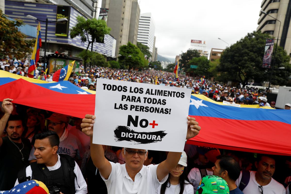 Demonstrators hold Venezuelan flags and a sign reads: ' All the food for all the people! No more dictatorship ' while rallying against Venezuela's President Nicolas Maduro in Caracas, Venezuela on May 1, 2017. (REUTERS/Carlos Garcia Rawlins)
