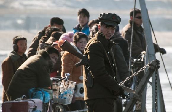 A North Korean soldier stands guard on a boat with locals on the Yalu River near the town of Sinuiju across from the Chinese border town of Dandong on Feb. 9, 2016. (JOHANNES EISELE/AFP/Getty Images)