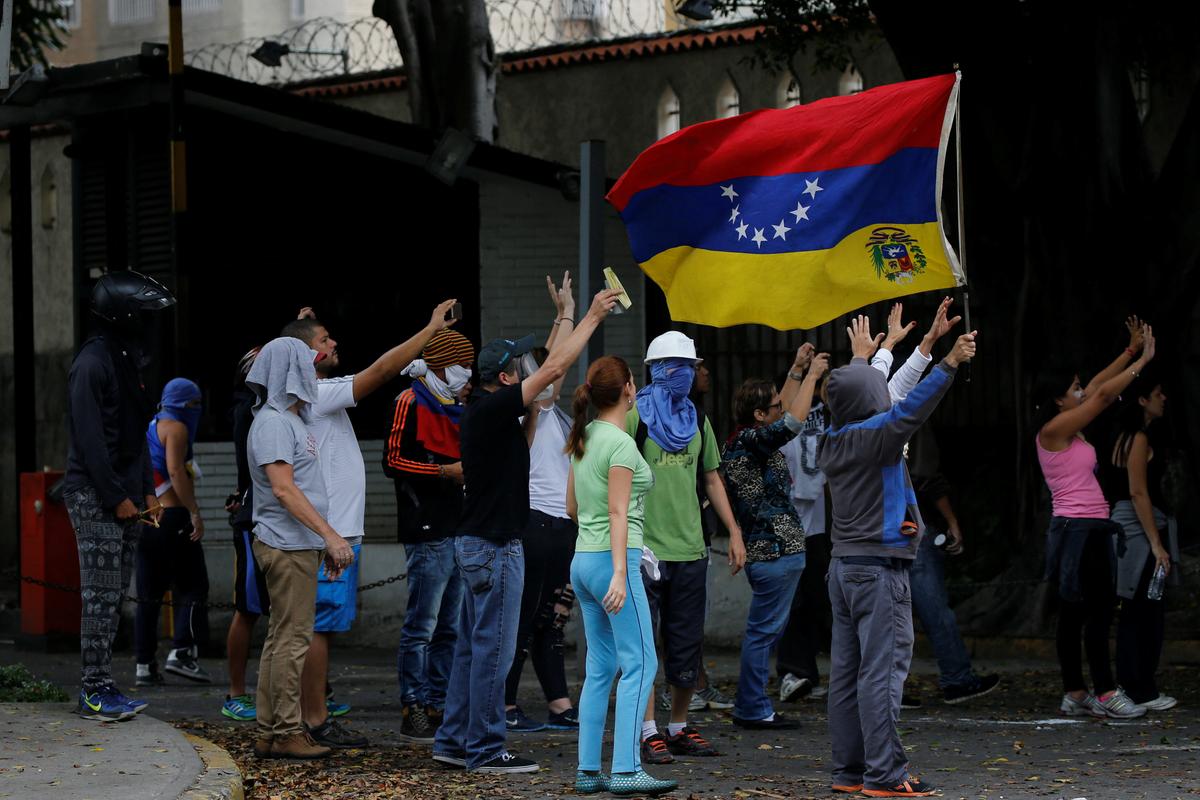 Opposition supporters wave a Venezuelan national flag as they clash with Venezuelan National guards during a protest against Venezuela's President Nicolas Maduro's government in Caracas, Venezuela on May 2, 2017. (REUTERS/Carlos Garcia Rawlins)