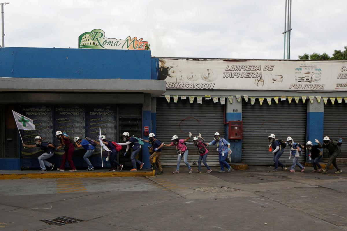 Volunteers, members of a primary care response team, walk together as demonstrators clash with police during a rally against Venezuela's socialist leader Nicolas Maduro in Caracas, Venezuela. (REUTERS/Marco Bello)