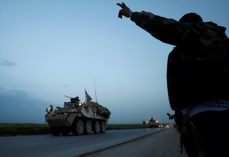 A Kurdish fighter from the People's Protection Units (YPG) gestures at a convoy of U.S military vehicles driving in the town of Darbasiya next to the Turkish border, Syria on April 28, 2017. (REUTERS/Rodi Said)