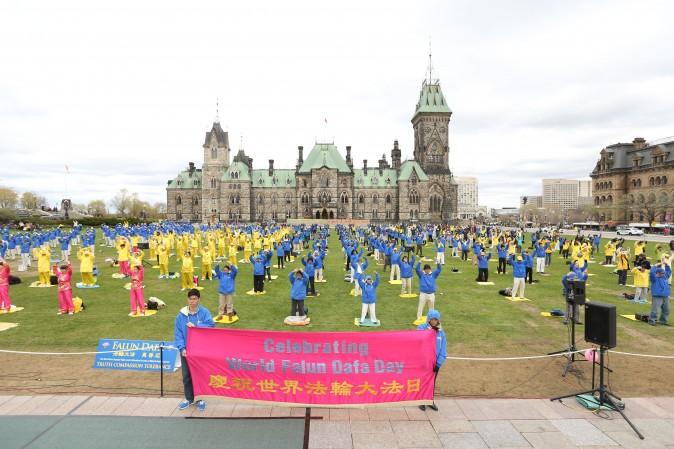 Falun Gong practitioners perform the slow-moving Falun Gong exercises during a celebration on Parliament Hill marking the 25th anniversary of the practice's introduction to the public, May 9, 2017. (Evan Ning/Epoch Times)