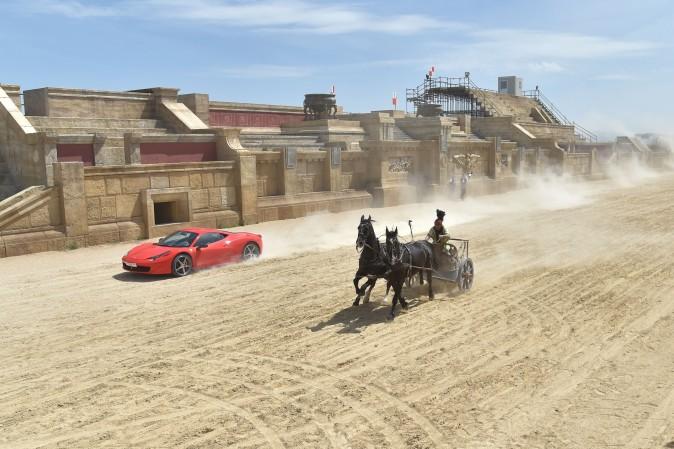 Driver Fabio Barone and his Ferrari 458 Italia competes against a Roman chariot drawn by two horses on 'Ben Hur' movie set at Cinecitta World amusement park in Castel Romano, Italy, on May 11, 2017 (ANDREAS SOLARO/AFP/Getty Images)