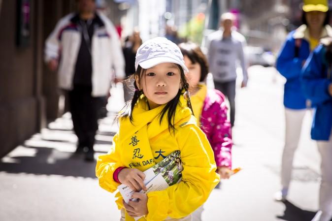 A little child passes out information about Falun Gong during a parade on World Falun Dafa Day in New York on May 12, 2017. (Samira Bouaou/The Epoch Times)
