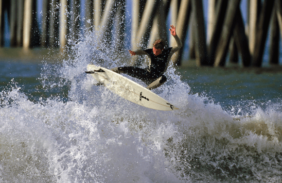 A surfer catches a wave near the pier. (Courtesy of Visit Huntington Beach)