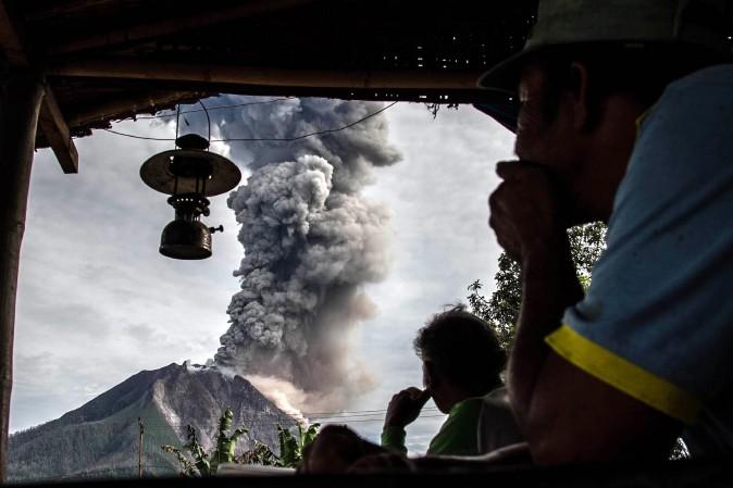 Villagers look on as Mount Sinabung volcano spews thick volcanic ash in Karo Regency, Indonesia, on May 19, 2017. Sinabung roared back to life in 2010 for the first time in 400 years. (IVAN DAMANIK/AFP/Getty Images)