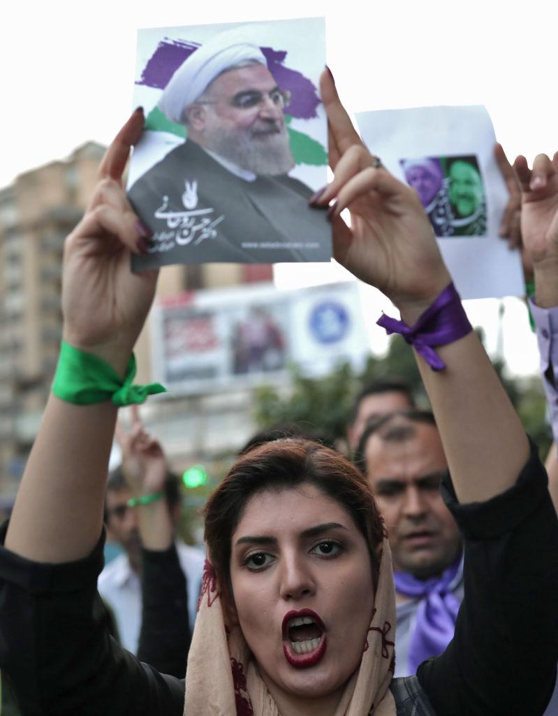 A supporter of newly re-elected Iranian President Hassan Rouhani holds a placard bearing a portrait of him as she takes to the streets to celebrate his victory in downtown Tehran on May 20, 2017.<br/>(BEHROUZ MEHRI/AFP/Getty Images)