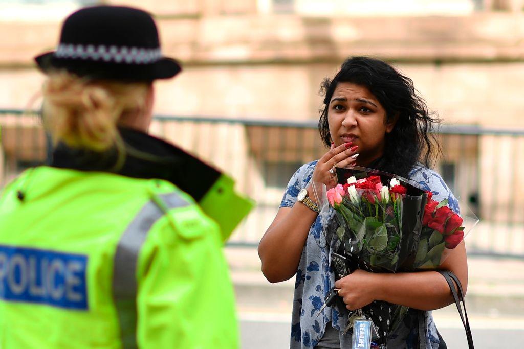 A police officer talks with a woman carrying a bunch of flowers near the Manchester Arena in Manchester, northwest England on May 23, 2017. (BEN STANSALL/AFP/Getty Images)