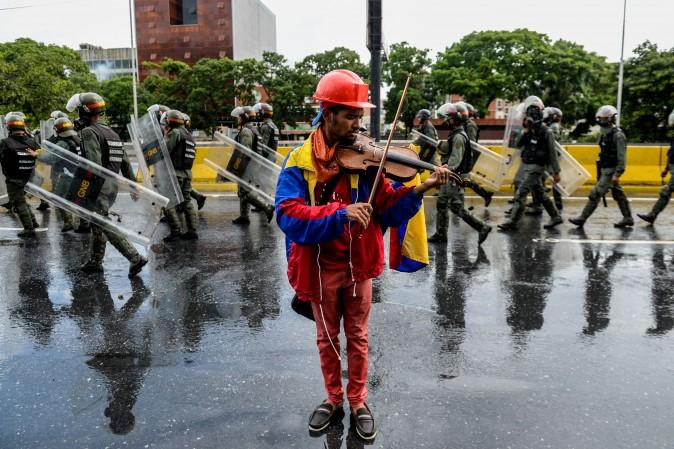 An opposition demonstrator plays the violin during a protest against President Nicolas Maduro in Caracas, Venezuela, on May 24, 2017. Venezuela's President Nicolas Maduro formally launched moves to rewrite the constitution on Tuesday, defying opponents who accuse him of clinging to power in a political crisis that has prompted deadly unrest. (FEDERICO PARRA/AFP/Getty Images)