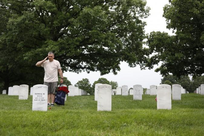 A volunteer salutes after laying a rose before a headstone at Arlington National Cemetery in Arlington, Va., on May 28, 2017. Volunteers from throughout the country gather to place a rose at each grave in preparation for Memorial Day. (Aaron P. Bernstein/Getty Images)