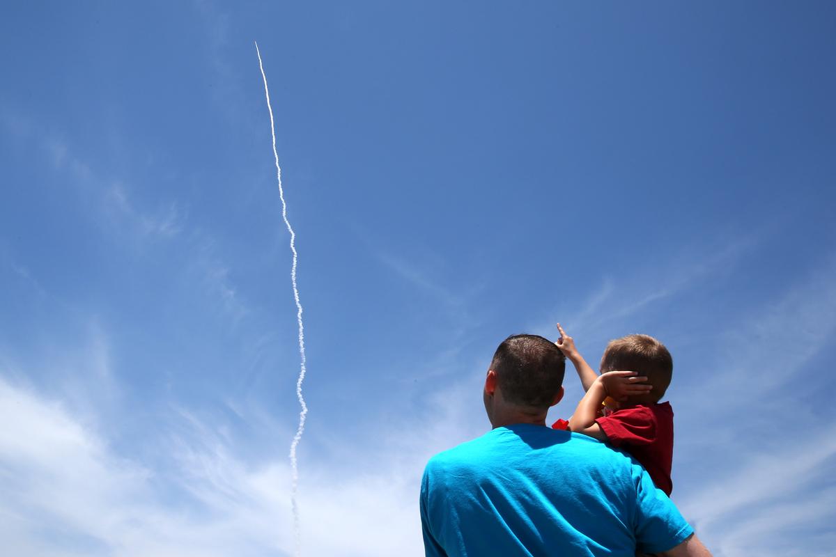 A man and a child watch as the Ground-based Midcourse Defense (GMD) element of the U.S. ballistic missile defense system launches during a flight test from Vandenberg Air Force Base, Calif., on May 30, 2017. (REUTERS/Lucy Nicholson)
