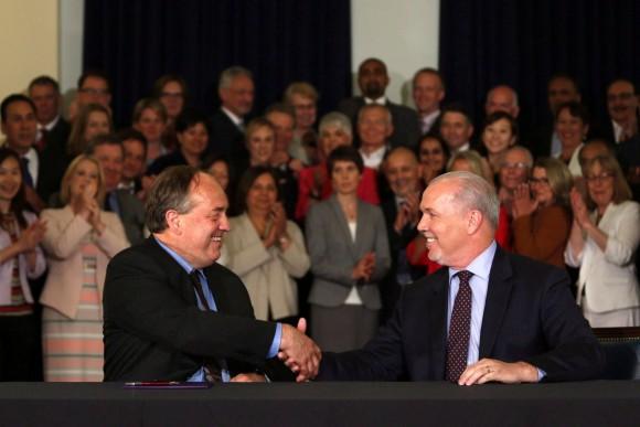 B.C. Green party leader Andrew Weaver (L) and B.C. NDP leader John Horgan shake hands after signing an agreement to create a stable minority government during a press conference at the Victoria legislature on May 30, 2017. (The Canadian Press/Chad Hipolito)