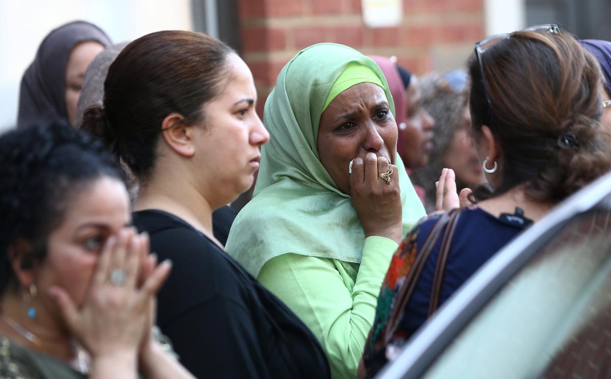 People react near a tower block severely damaged by a serious fire, in north Kensington, West London, Britain on June 14, 2017. (REUTERS/Neil Hall)