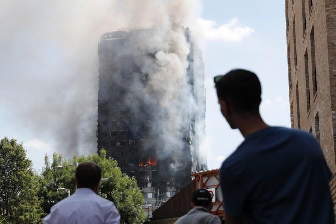 Pedestrians look up towards Grenfell Tower, a residential block of flats in west London on June 14, 2017, as firefighters continue to control a fire that engulfed the building in the early hours of the morning.<br/>Shaken survivors of a blaze that ravaged a west London tower block told Wednesday of seeing people trapped or jump to their doom as flames raced towards the building's upper floors and smoke filled the corridors. ( ADRIAN DENNIS/AFP/Getty Images)