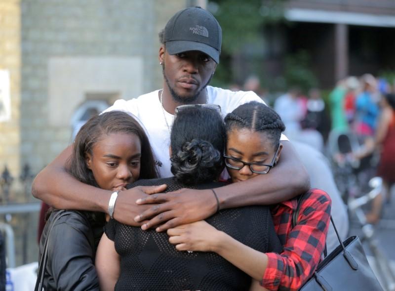 People comfort each other after a prayer vigil outside Notting Hill Methodist Church close to the tower block severely damaged by a serious fire, in north Kensington, West London. (REUTERS/Paul Hackett)