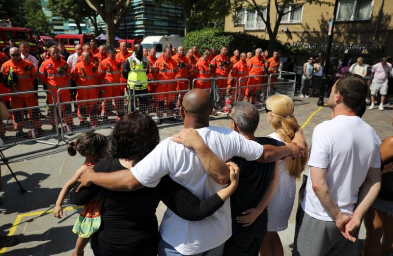 Members of the emergency services join people in a minute's silence for the victims of the Grenfell Tower fire near the site of the blaze in North Kensington, London on Britain, June 19, 2017. (REUTERS/Marko Djurica)