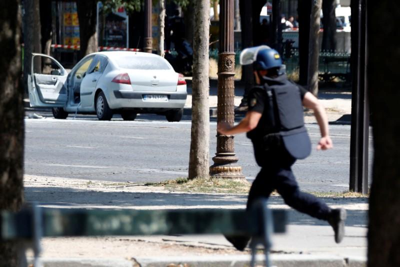 A French gendarme runs past a car on the Champs Elysees avenue after an incident in Paris, France, June 19, 2017. REUTERS/Charles Platiau