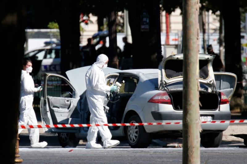 Members of the scientific police inspect a burned car at the scene of an incident in which a car rammed a gendarmerie van on the Champs-Elysees Avenue in Paris, France, June 19, 2017. (REUTERS/Gonzalo Fuentes)