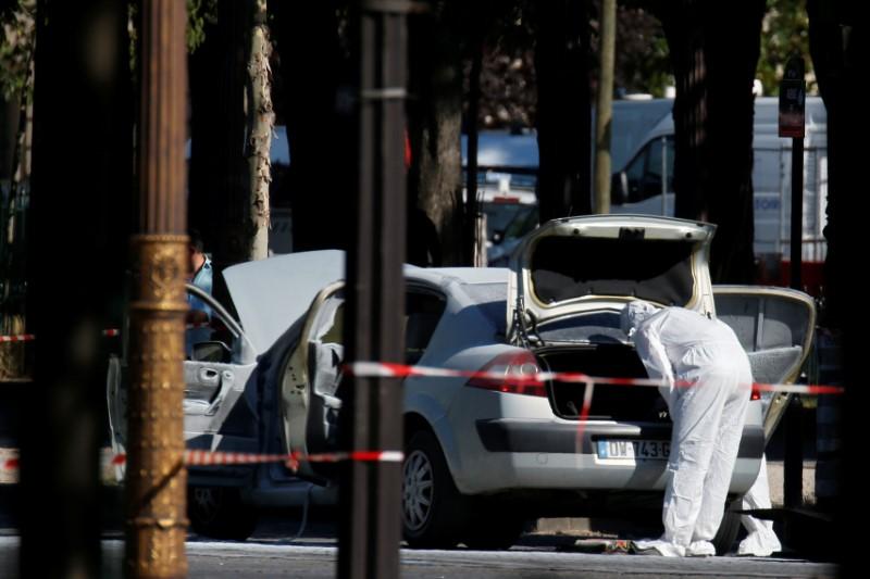 A member of the scientific police inspects a burned car at the scene of an incident in which a car rammed a gendarmerie van on the Champs-Elysees Avenue in Paris, France, June 19, 2017. REUTERS/Gonzalo Fuentes