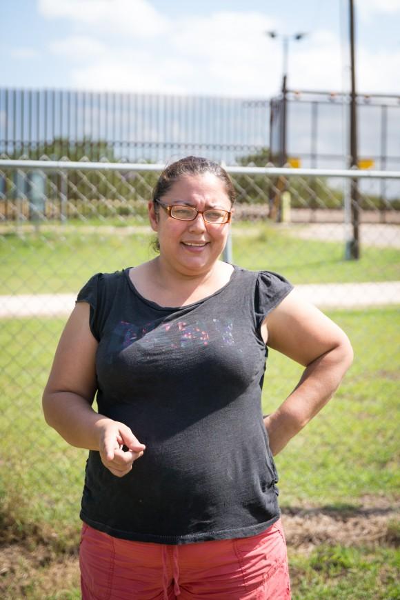 Noelia Guerra in her yard with the border fence behind her in Brownsville, Texas, on June 1, 2017. She has seen many illegal immigrants scale the 18-foot fence and hide in the trees behind her property. (Benjamin Chasteen/The Epoch Times)